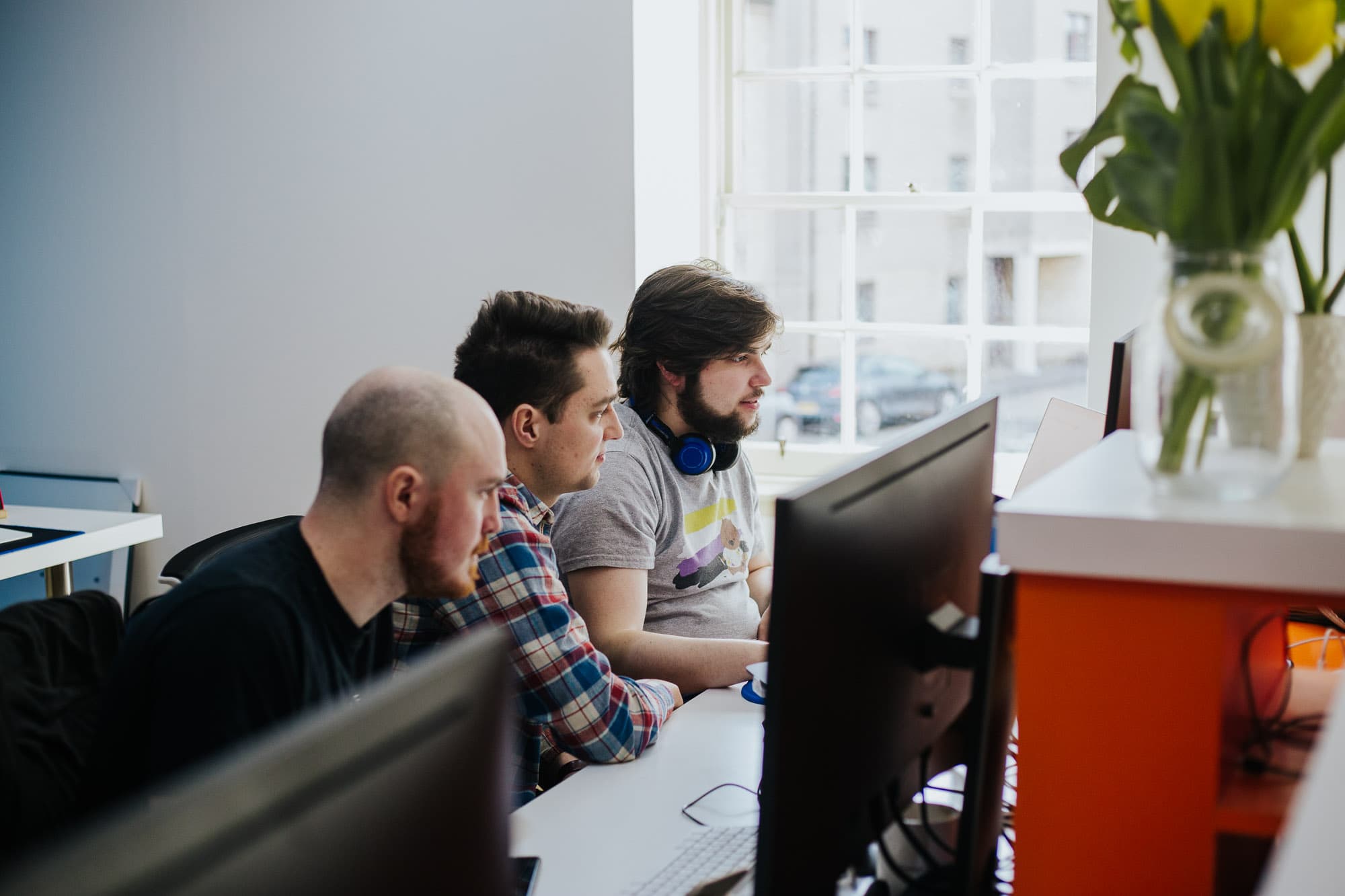 A developer at their desk with a code editor open across a large monitor and laptop